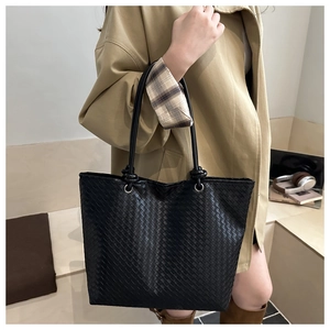 Detailed view of the black woven texture and leather handle of a minimalist tote bag