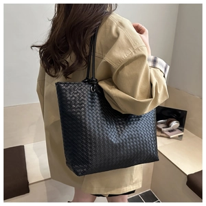 Close-up of black woven leather tote bag texture and long shoulder straps for daily wear