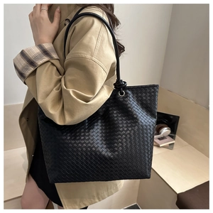Detail of black woven tote bag with leather texture and thin shoulder straps for work