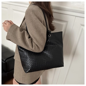 Macro view of woven leather texture and silver metal rings on black large tote bag