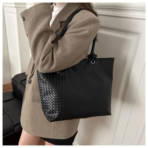 Detailed view of large black woven leather tote bag with stylish knot shoulder strap detail