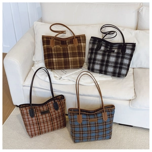 Detail shot of four retro plaid tote bags in various autumn colors on a white sofa