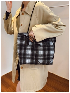 Woman in khaki trench coat carrying a large black and white checkered plush tote bag