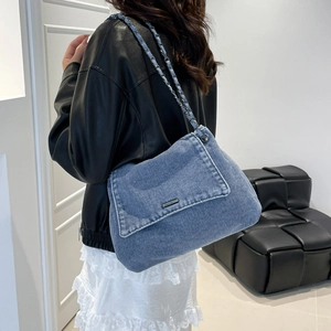 Blue denim chain shoulder bag with metal logo plate shown in a lifestyle model shot