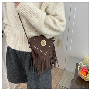 Detail of bohemian fringe crossbody bag with studded suede and sun-shaped metal ornament