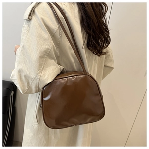 Minimalist dark brown glossy shoulder bag styled on a beige trench coat for winter