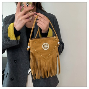 Detail of yellow faux suede saddle bag featuring bohemian fringe and studded rhinestone emblem