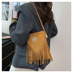 Detail view of mustard yellow suede bag with metallic rivets and long boho fringe tassels