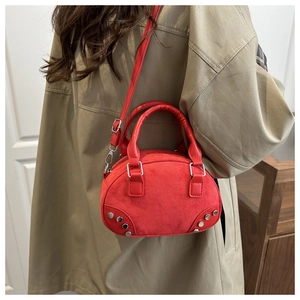 Red suede crossbody bag with silver rivet details shown on a model for scale and fit