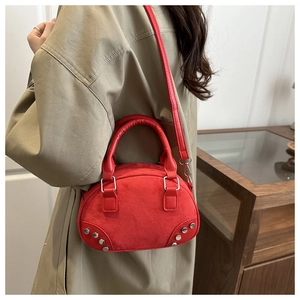 Detail of red suede shell bag with silver rivets worn over a green winter coat