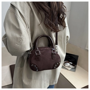Rear view of model wearing a brown suede bowling bag with vintage silver rivet details
