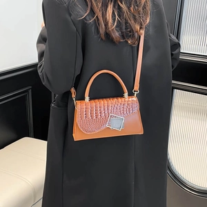 Warm brown crossbody bag with crocodile pattern flap and silver buckle detail