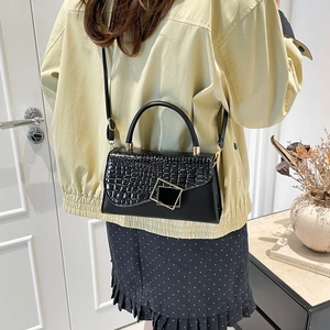 Chic black crocodile embossed flap bag with gold geometric lock on minimalist background