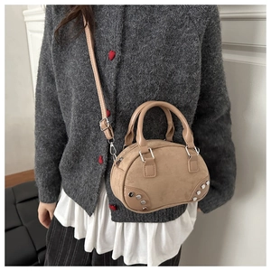 Detail of suede crossbody bowling bag with rivets and adjustable strap on a model
