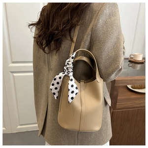 Detail of light brown lychee grain leather bucket bag with a decorative polka dot scarf wrap