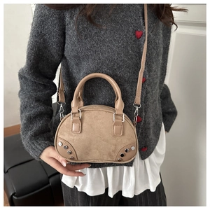Detail of studded khaki bowling bag with suede texture and smooth leather trim
