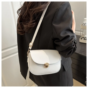 Detail of white lychee leather saddle bag with gold metal lock and wide strap