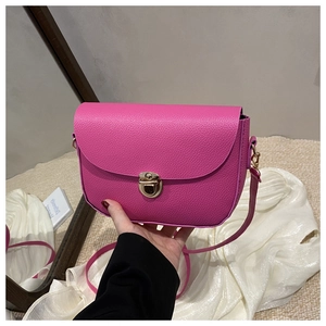 Detailed close-up of rose red lychee leather saddle bag with gold metal buckle clasp
