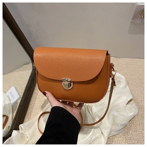 Close-up of orange lychee grain leather saddle bag with elegant gold metal push-lock