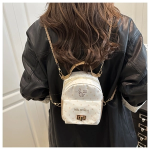 Détail du mini sac à dos blanc à pois avec motif chat et bretelles chaîne dorée