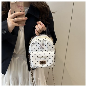 Détail d'un mini sac à dos blanc à pois avec illustration de chat et chaîne dorée