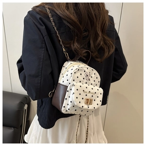 Détail du mini sac à dos à pois avec finitions en cuir marron et bandoulière chaîne