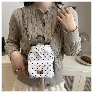 Close-up of polka dot mini backpack with cartoon cat print and gold chain strap
