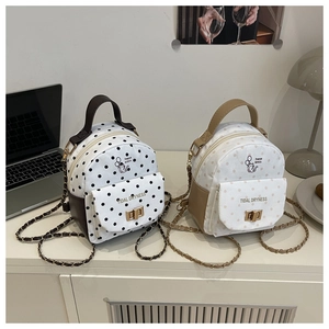 Detail of cute polka dot mini backpack with cat print and metal chain strap on desk