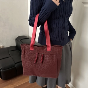 Deep burgundy leopard print tote bag with red handles shown as a shoulder bag on a model