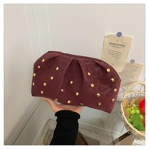 Close-up of burgundy pleated clutch bag with gold studs and matte leather texture