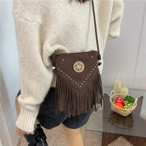 Brown suede tassel crossbody bag with gold rivets and vintage saddle design on sofa