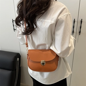 Orange lychee leather saddle bag with gold swivel lock shown on a female model