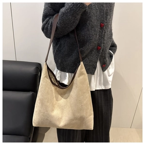 Detail of suede tote bag with brown leather straps shown on shoulder for daily commute
