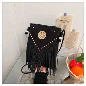 Detail of bohemian fringe crossbody bag with gold studs and vintage medallion