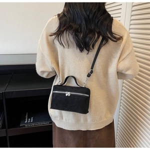 Détail d'un sac boîte noir mat avec fermetures éclair en forme de cœur argentées et poignée