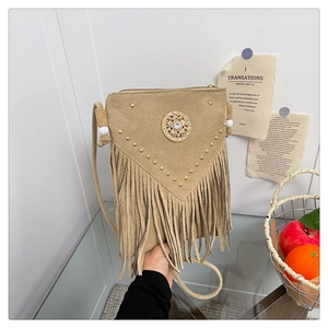 Detail of bohemian khaki fringe bag featuring metal rivets and rhinestone circular accent