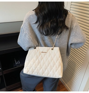 Détail d'un sac cabas matelassé blanc avec logo métallique et bandoulière en chaîne