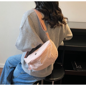 Détail du sac à bandoulière en nylon rose avec texture froissée et bandoulière large