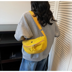 Dettaglio della borsa a mezzaluna in nylon giallo con logo rotondo e zip a triangolo