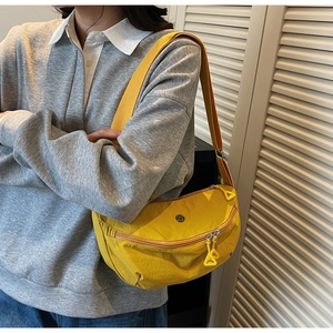 Détail du sac dumpling jaune en nylon avec sangle tissée et tirette triangulaire