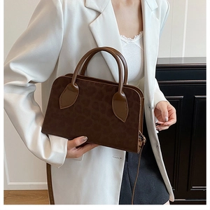 Detail of dark brown leopard embossed tote with matte leather texture and sleek handle