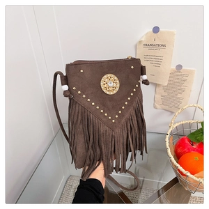 Close-up of bohemian brown suede crossbody bag with fringe tassels and sun-pattern metal buckle