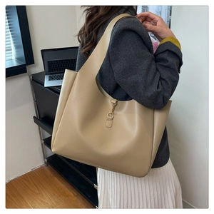 Detail of minimalist beige leather tote bag with golden metal clasp and spacious interior