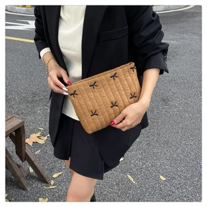 Gros plan sur la pochette matelassée marron avec broderie de nœuds noirs et texture douce