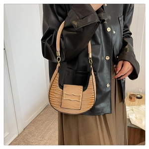 Close-up of beige crocodile pattern texture and golden metal buckle on crescent bag