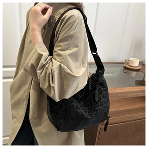 Detail of hobo bag with leopard print textile texture and adjustable black wide shoulder strap