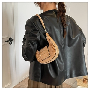 Detail of light brown crocodile-embossed crescent bag with metallic buckle detail
