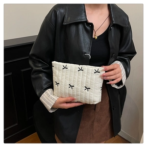 Détail du sac à main matelassé crème avec nœuds noirs et texture en tissu doux