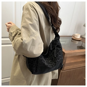 Detail of black leopard print crossbody bag worn with a stylish beige trench coat