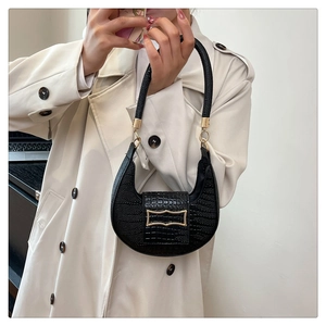 Close-up of black crocodile pattern on crescent bag with a gold metal ring clasp detail